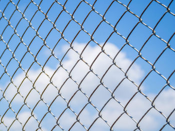 Low angle view of blue sky seen through chainlink fence