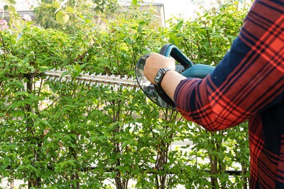 Midsection of man holding lawn mower