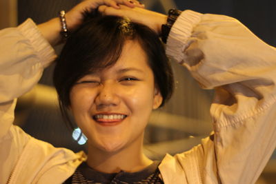 Close-up portrait of young woman winking at night