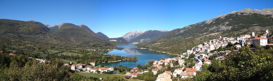 Panoramic view of lake and buildings against clear blue sky