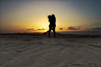 Silhouette man standing on beach against sky during sunset