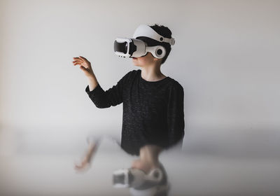 Boy gesturing while using virtual reality against white background