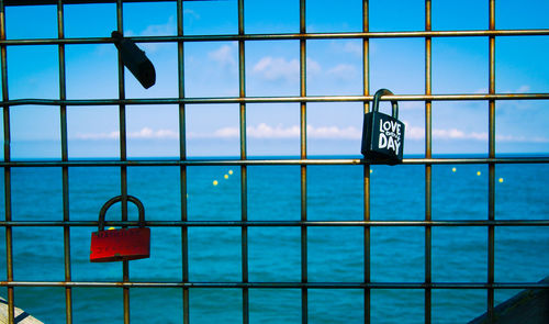 Information sign on railing by sea against blue sky