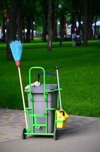 Garbage can with broom against park