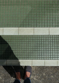 Low section of person standing by swimming pool