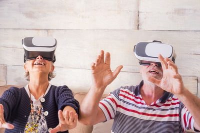 Senior couple wearing virtual reality simulator at home