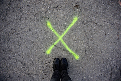 Low section of man standing by cross mark on street