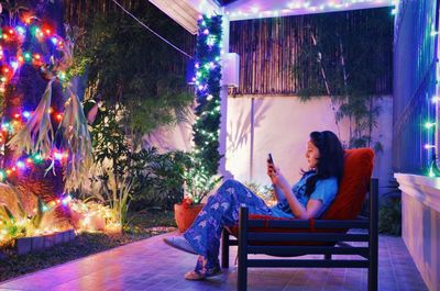 Young woman sitting on chair at night