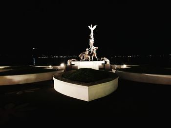 Statue against illuminated sky at night