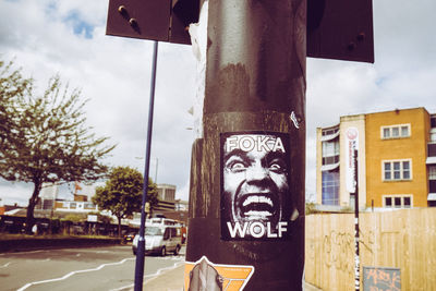 Close-up of road sign against sky in city