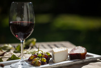 Close-up of red wine and cheese on wooden table