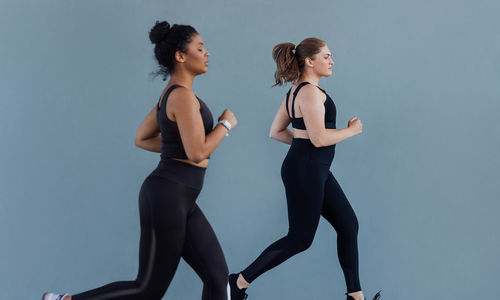 Side view of woman exercising against blue background