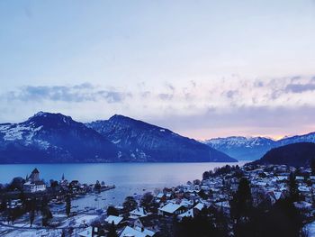 Scenic view of sea by snowcapped mountains against sky