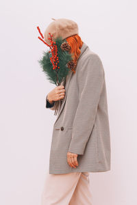 Portrait of woman holding flowers against white background