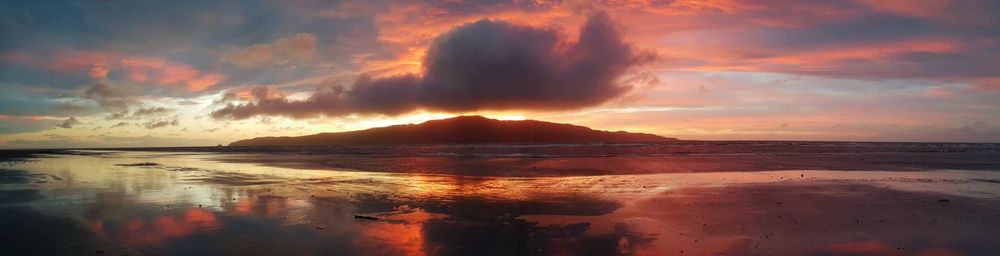 Panoramic view of sea against dramatic sky during sunset