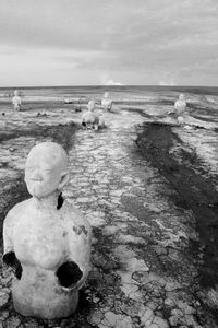 Old ruined sculptures on field against sky