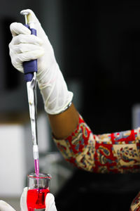 Cropped hand of scientist wearing surgical glove while working in laboratory