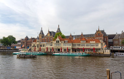 View of buildings by river against cloudy sky