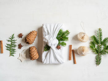 Flat lay fabric wrapped gift with fir tree branch and nature decor. 