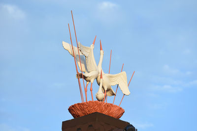 Low angle view of a bird sculpture against blue sky