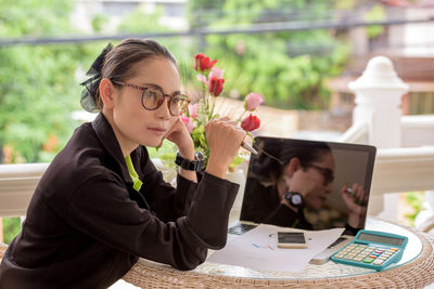 Side view of young woman using mobile phone at table