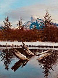 Frozen lake by snowcapped mountains against sky