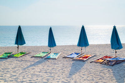 Lounge chairs and parasols on beach against sky