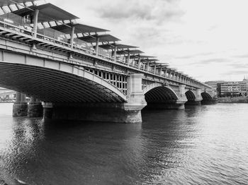 Arch bridge over river against sky in city