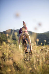 Woman with arms outstretched on field against sky