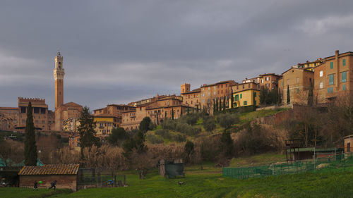 Buildings in city against cloudy sky