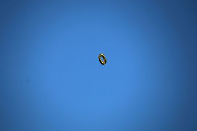 Low angle view of balloon flying against clear blue sky
