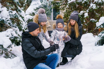 Friends standing on snow covered tree during winter