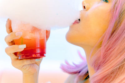 Close-up of woman eating cotton candy over drink 