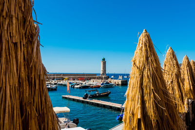 Boats moored in sea against clear blue sky