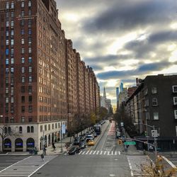 View of city street against cloudy sky