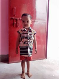 Portrait of boy standing against door