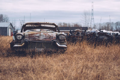 Abandoned car on field against sky