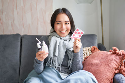 Portrait of young woman holding ice cream at home