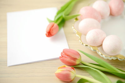 Close up of easter eggs with blank paper and tulips on table
