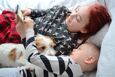 Siblings using mobile phone on bed at home