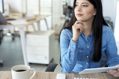 Close-up of woman holding coffee cup on table