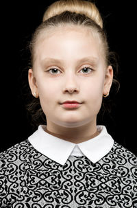 Close-up portrait of teenage girl against black background