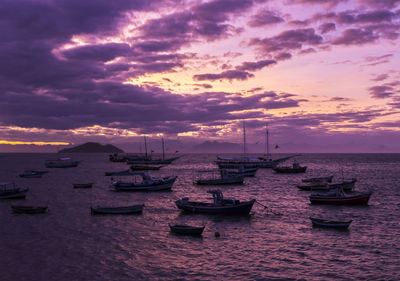 Boats moored on sea against sky during sunset