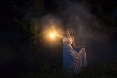 Woman with illuminated light on field at night