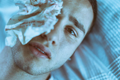 Close-up portrait of man with crumpled paper on eye