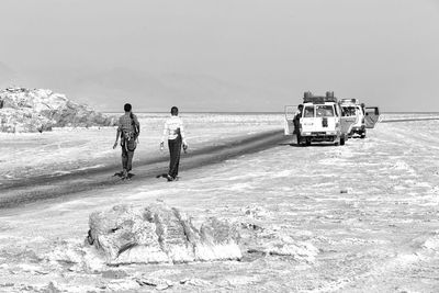 Rear view of people at beach against sky