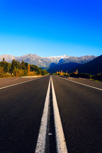 Road amidst mountains against clear blue sky