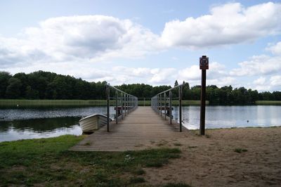 Empty pier over lake against sky