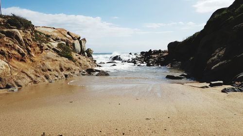 Rock formations on beach against sky