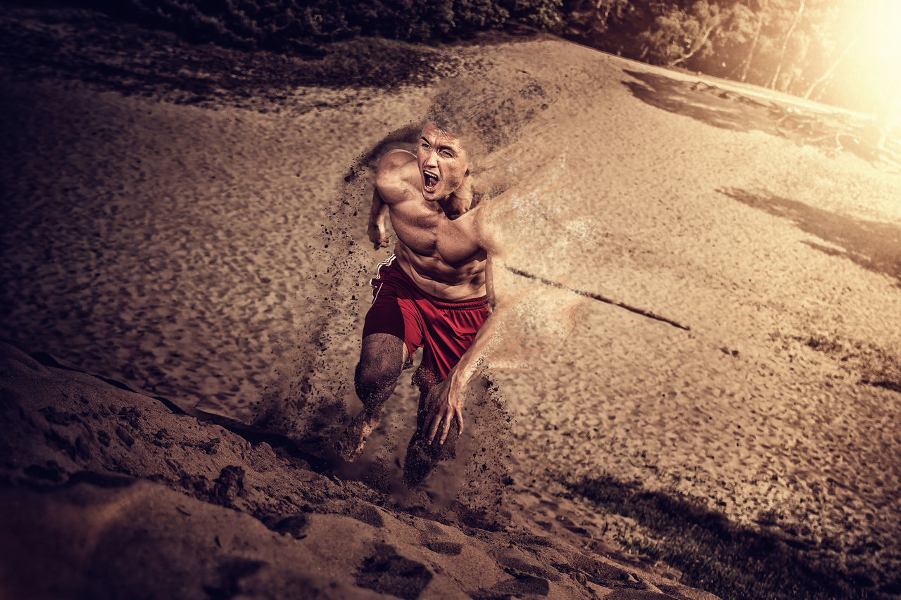 FULL LENGTH OF SHIRTLESS MAN LYING ON SAND AT BEACH